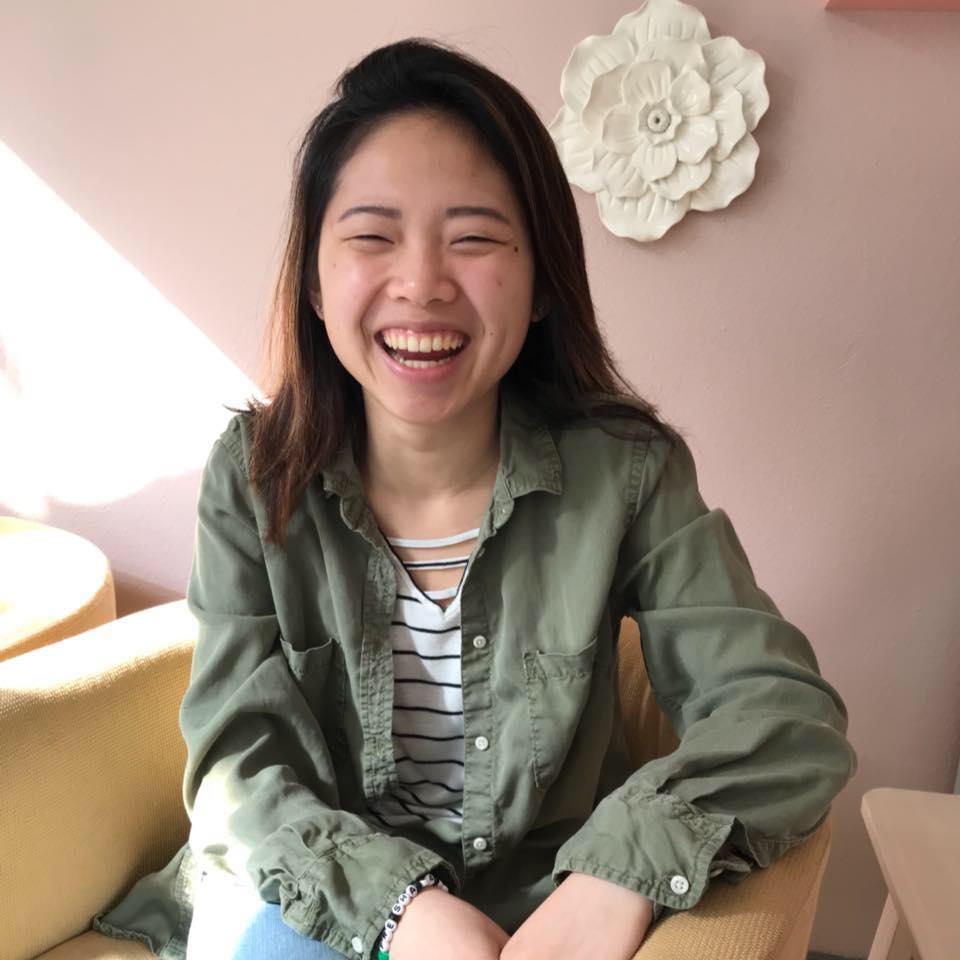 Image of Erin Hawkins smiling sitting in front of a pink wall